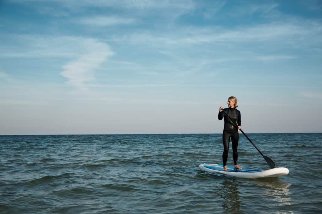 Young blonde female paddles a paddleboard at the sea